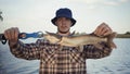 Young fisherman actively fishing at lake. Man demonstrates the caught pike Royalty Free Stock Photo