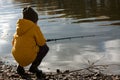 Young fisherman. boy in yellow jacket and rubber boots is fishing while standing in water on river bank. Leisure outdoors. gold Royalty Free Stock Photo