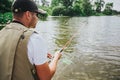 Young fisherman fishing on lake or river. Back view of concentrated guy waiting to catch some fish. Man holding fish-rod Royalty Free Stock Photo