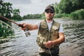 Young fisherman fishing on lake or river. Picture of man doing active fishing with holding rod in hand. Stand alone in Royalty Free Stock Photo