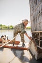 Young fisherman in panama hat untying rowing boat from wharf, while going fishing with dog. Royalty Free Stock Photo