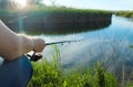 A young fisherman stands by the lake holding a fishing rod side view on a bright sunny summer day Royalty Free Stock Photo