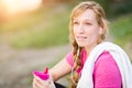 Young Fit Adult Woman Outdoors With Towel and Water Bottle in Workout Clothes Listening To Music with Earphones. Royalty Free Stock Photo