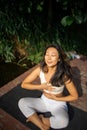 Young fit asian woman doing yoga by the lake in the morning park Royalty Free Stock Photo
