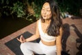 Young fit asian woman doing yoga by the lake in the morning park Royalty Free Stock Photo