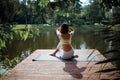 Young fit asian woman doing yoga by the lake in the morning park Royalty Free Stock Photo