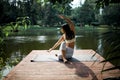 Young fit asian woman doing yoga by the lake in the morning park Royalty Free Stock Photo