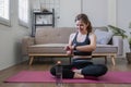 Young fit Asian woman sits on the floor and looks at her smart watch in the living room. An athlete is viewing her Royalty Free Stock Photo