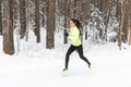 Young fit athlete woman running at forest Sprinting during winter training outside in cold snow weather.