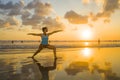 Young fit and attractive sport woman in beach sunset yoga practice workout on wet sun in front of the sea in meditation and relaxa