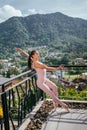 Young fit ballerina pink pointes dancing on toes against mountainous landscape