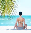 Young, fit and beautiful girl meditating on a summer beach Royalty Free Stock Photo