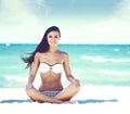 Young, fit and beautiful girl meditating on a summer beach Royalty Free Stock Photo