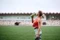 Young fit blond woman, wearing orange top and green leggings, drinking water from light green bottle, Refresh yourself during Royalty Free Stock Photo