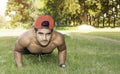 Young fit Caucasian man with muscular body doing push-ups outdoors on sunny summer day Royalty Free Stock Photo