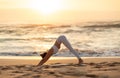 Young fit caucasian woman practicing yoga, doing exercise, asana enjoying workout on sea beach at sunset, side view Royalty Free Stock Photo