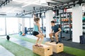 Young fit couple exercising in gym, doing box jumps. Royalty Free Stock Photo