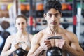 Young fit couple in gym exercising with kettlebell. Royalty Free Stock Photo