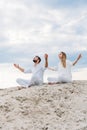young fit couple on yogi meditating while sitting on sandy dune in lotus pose