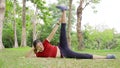 Young fit happy Asian woman, laying side way, working on her lef lifting routine during her morning exercise at a local park on an