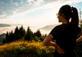 Young fit happy woman hike pass in mountains. Carefree tourist woman looking at sun enjoying landscape. Girl traveler on top of Royalty Free Stock Photo