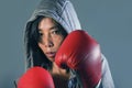 Young fit and healthy Asian Korean boxer woman in fitness top hoodie and boxing gloves posing cool badass attitude angry and defia Royalty Free Stock Photo