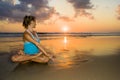 Young fit and healthy attractive woman practicing fitness and yoga in beautiful sunset beach in meditation and relaxation concept Royalty Free Stock Photo