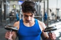 Young fit hispanic man in gym exercising with dumbbells. Royalty Free Stock Photo