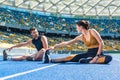 young fit male and female joggers sitting on running track and stretching Royalty Free Stock Photo
