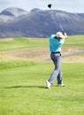 Driving it down the fairway. A young, fit male golfer following through after driving his ball down the fairway. Royalty Free Stock Photo