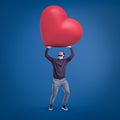 Young fit man in casual clothes holding up huge red Valentine heart on blue background. Royalty Free Stock Photo