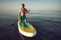 Young fit man on paddle board floating on lake. Royalty Free Stock Photo