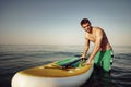 Young fit man on paddle board floating on lake. Royalty Free Stock Photo