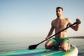 Young fit man on paddle board floating on lake. Royalty Free Stock Photo