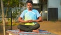 Young fit man wearing sportswear meditating, breathing, sitting with crossed legs in Half Lotus Posture at home Royalty Free Stock Photo