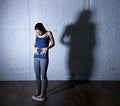 Young fit and slim woman checking body weight on scale with big edgy shadow light sad and desperate Royalty Free Stock Photo