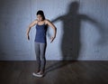 Young fit and slim woman checking body weight on scale with big edgy shadow light sad and desperate Royalty Free Stock Photo