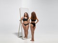 Young fit, slim woman looking at fat girl in mirror`s reflection on white background Royalty Free Stock Photo