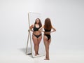 Young fit, slim woman looking at fat girl in mirror`s reflection on white background Royalty Free Stock Photo