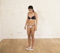 Young fit slim woman or teen girl checking body weight on scale finding herself fat