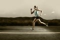 Young fit sport woman running outdoors on asphalt road in mountain landscape and dramatic light set for advertising Royalty Free Stock Photo