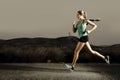 Young fit sport woman running outdoors on asphalt road in mountain landscape and dramatic light set for advertising Royalty Free Stock Photo