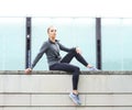Young, fit and sporty woman sitting on a concrete border. Fitness, sport, urban jogging and healthy lifestyle concept. Royalty Free Stock Photo