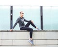 Young, fit and sporty girl sitting on a concrete border. Fitness, sport, urban jogging and healthy lifestyle concept. Royalty Free Stock Photo