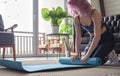 Young fit sporty girl unrolling mat before fitness yoga training at home. Royalty Free Stock Photo