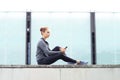 Young, fit and sporty woman sitting on a concrete border. Fitness, sport, urban jogging and healthy lifestyle concept. Royalty Free Stock Photo