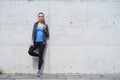 Young, fit and sporty woman standing in front of concrete cement wall. Fitness, sport, urban jogging and healthy