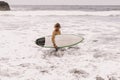 young fit surfer man with surfboard runs into ocean or sea with big waves for surfing. Concept of extreme sport, fitness Royalty Free Stock Photo