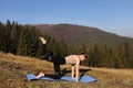 Young fit woman doing exercises on yoga mat on background of sunny mountains hills. Outdoor workout, healthy lifestyle. female in Royalty Free Stock Photo