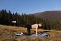 Young fit woman doing exercises on yoga mat on background of sunny mountains hills. Outdoor workout, healthy lifestyle. female in Royalty Free Stock Photo